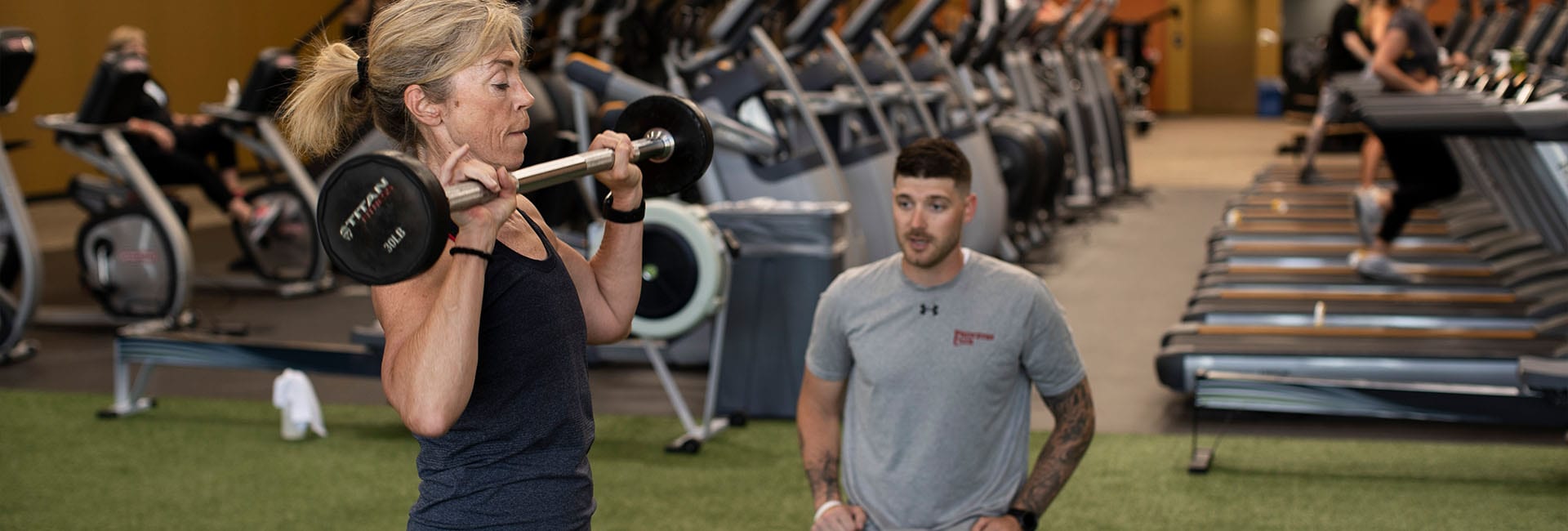 Personal trainer helping a client lift weights.