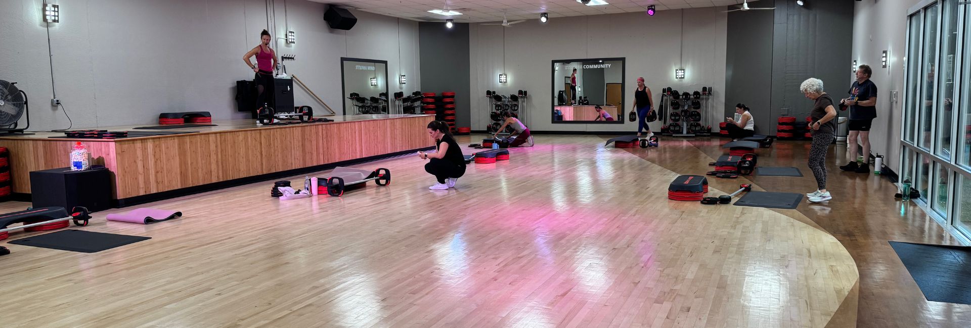 Princeton Club group fitness studio with a wood floor, stage, and members set up for a fitness class