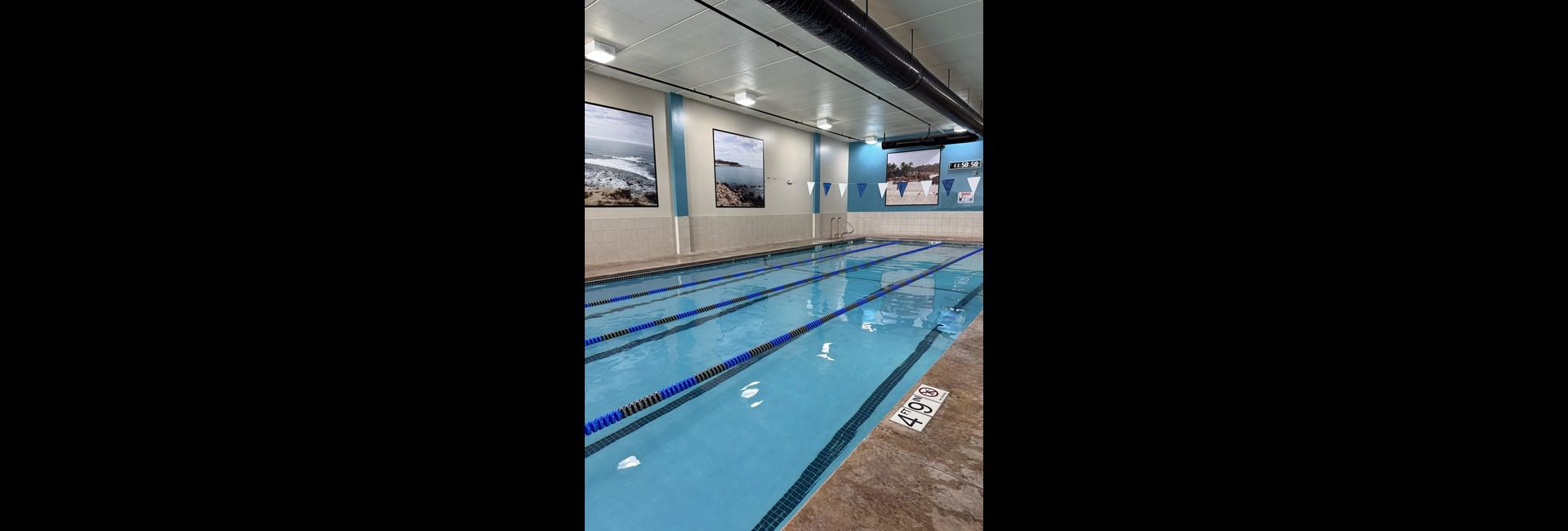 Princeton Club Fitchburg indoor lap pool with marked swim lanes, pool deck and timing clock — renovated aquatics facility (2025)